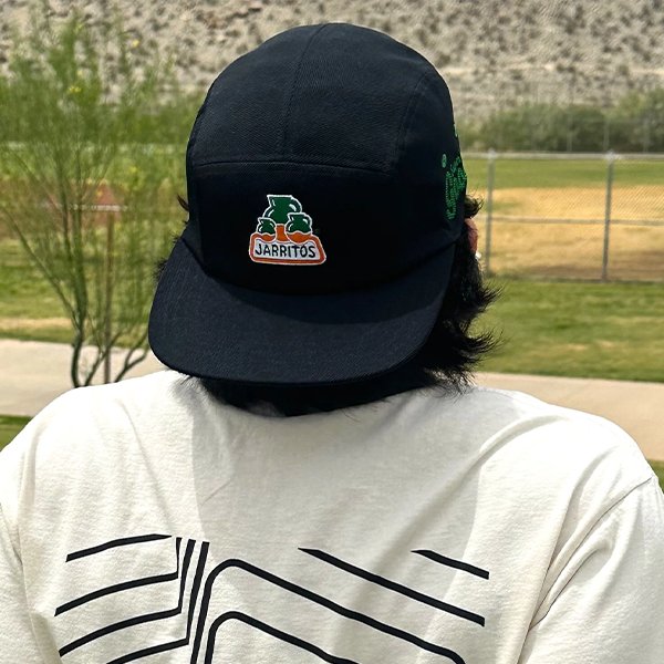 Jarritos cap on illustrated fruit-print backdrop